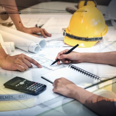People working at A table of blue prints and hard hats